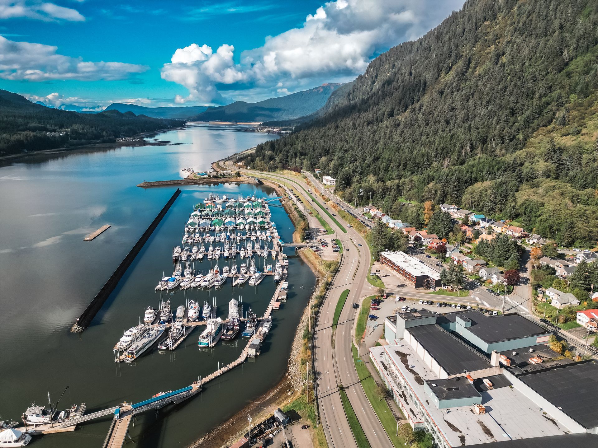 An aerial view of a marina with boats docked and mountains in the background.