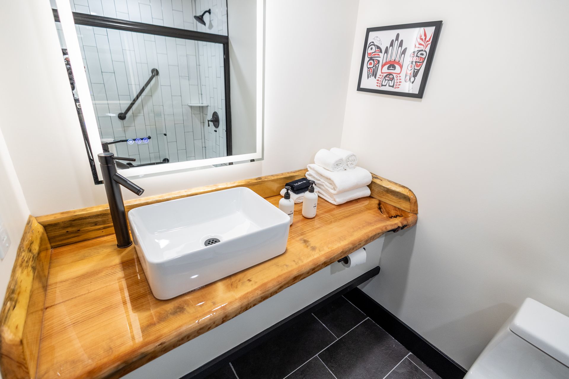 A bathroom with a sink , toilet , mirror and shower.