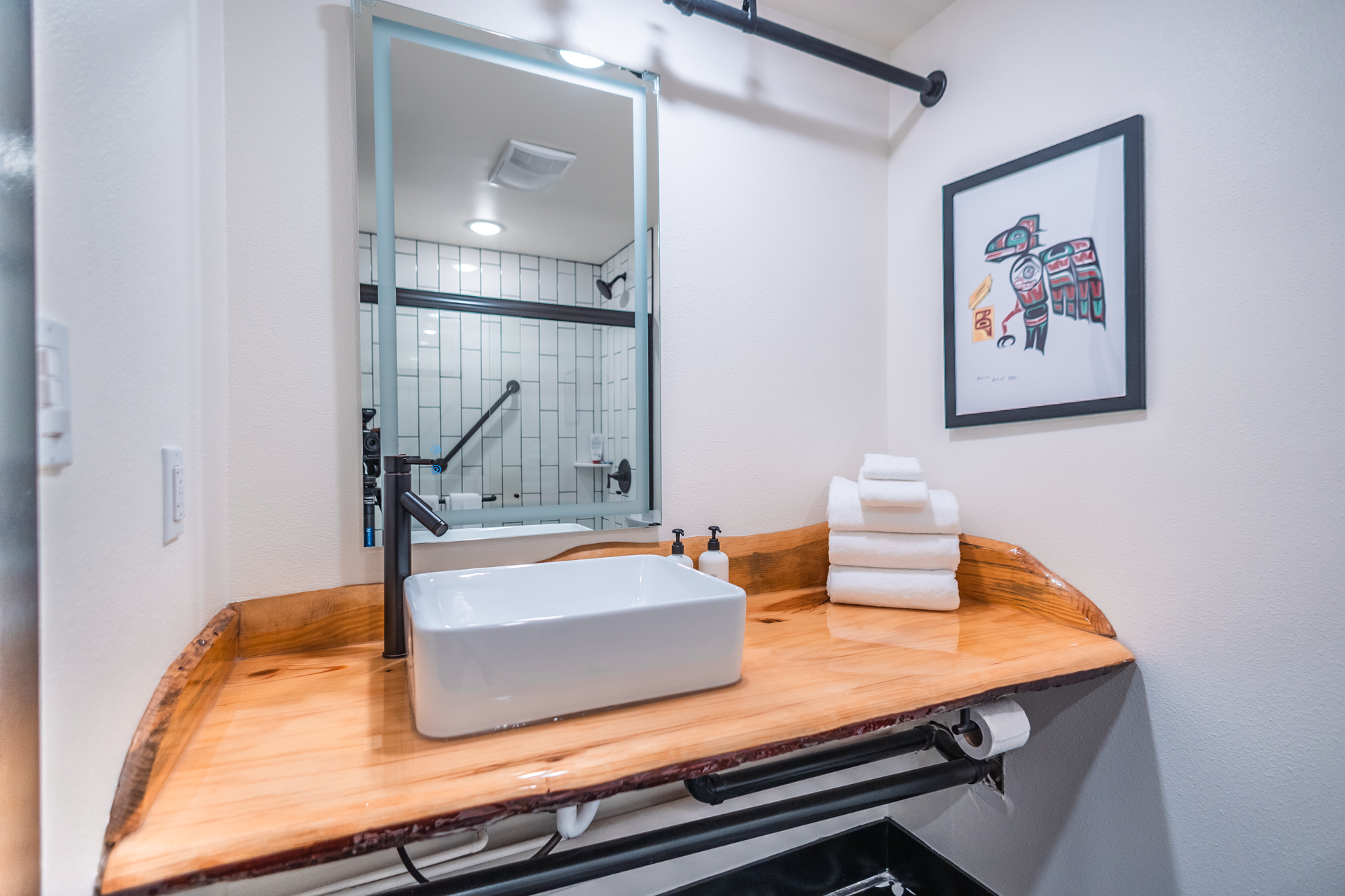 A bathroom with a sink , mirror , and wooden counter top.