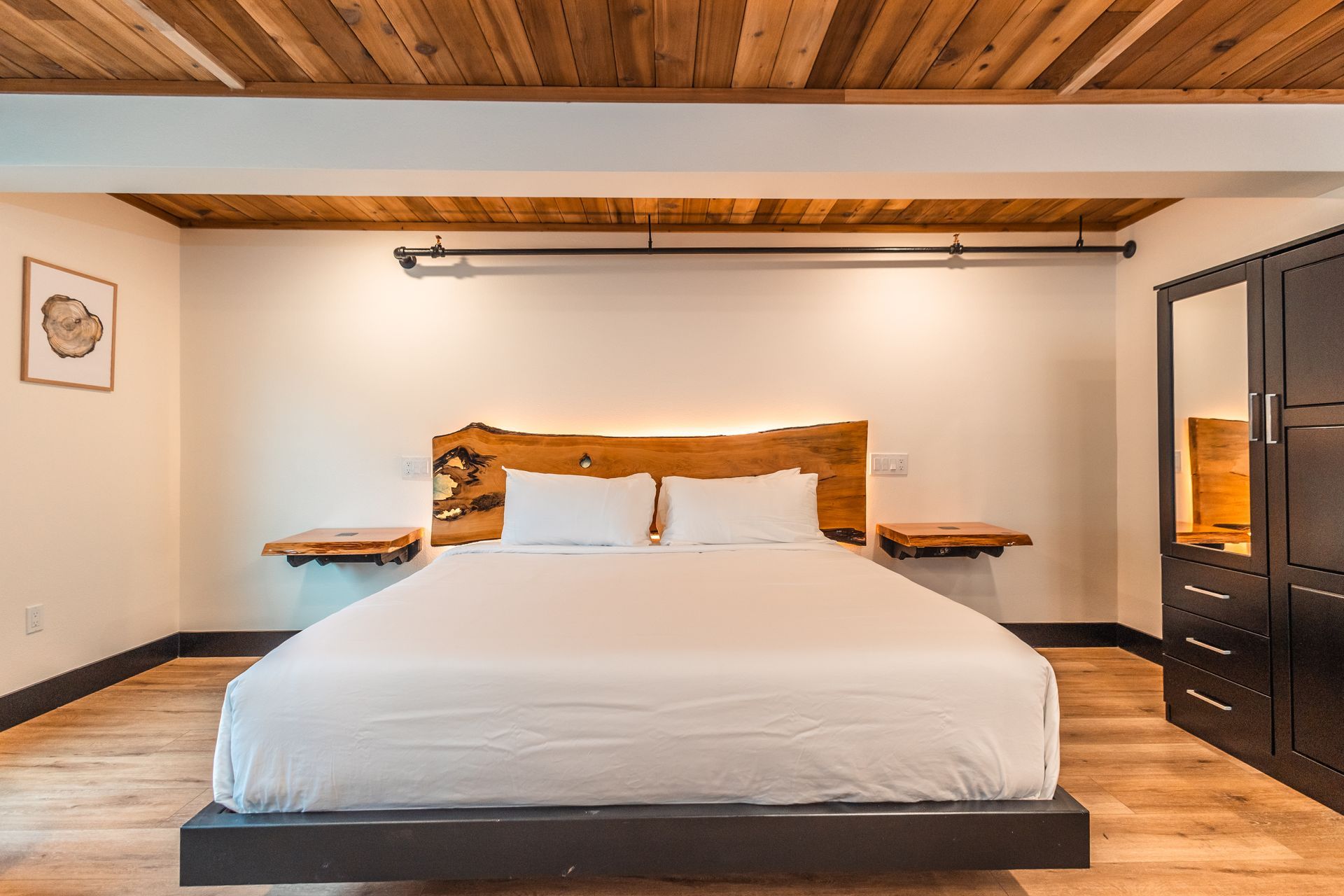 There is a large bed in the middle of the room with a wooden headboard.