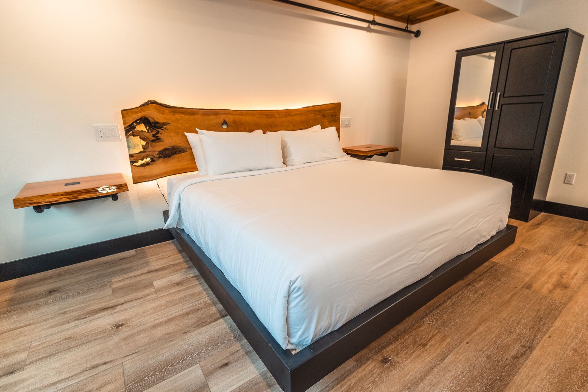 A hotel room with a king size bed and a wooden headboard.