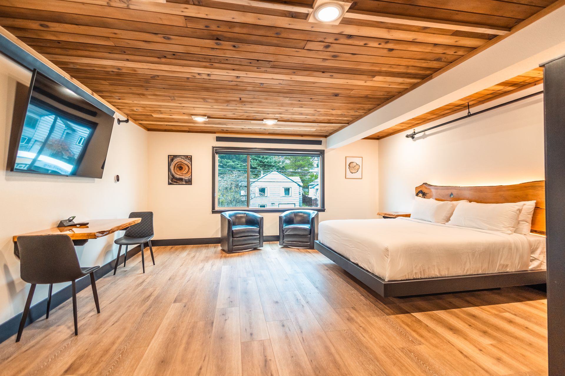 A hotel room with a king size bed , chairs , a desk and a flat screen tv.