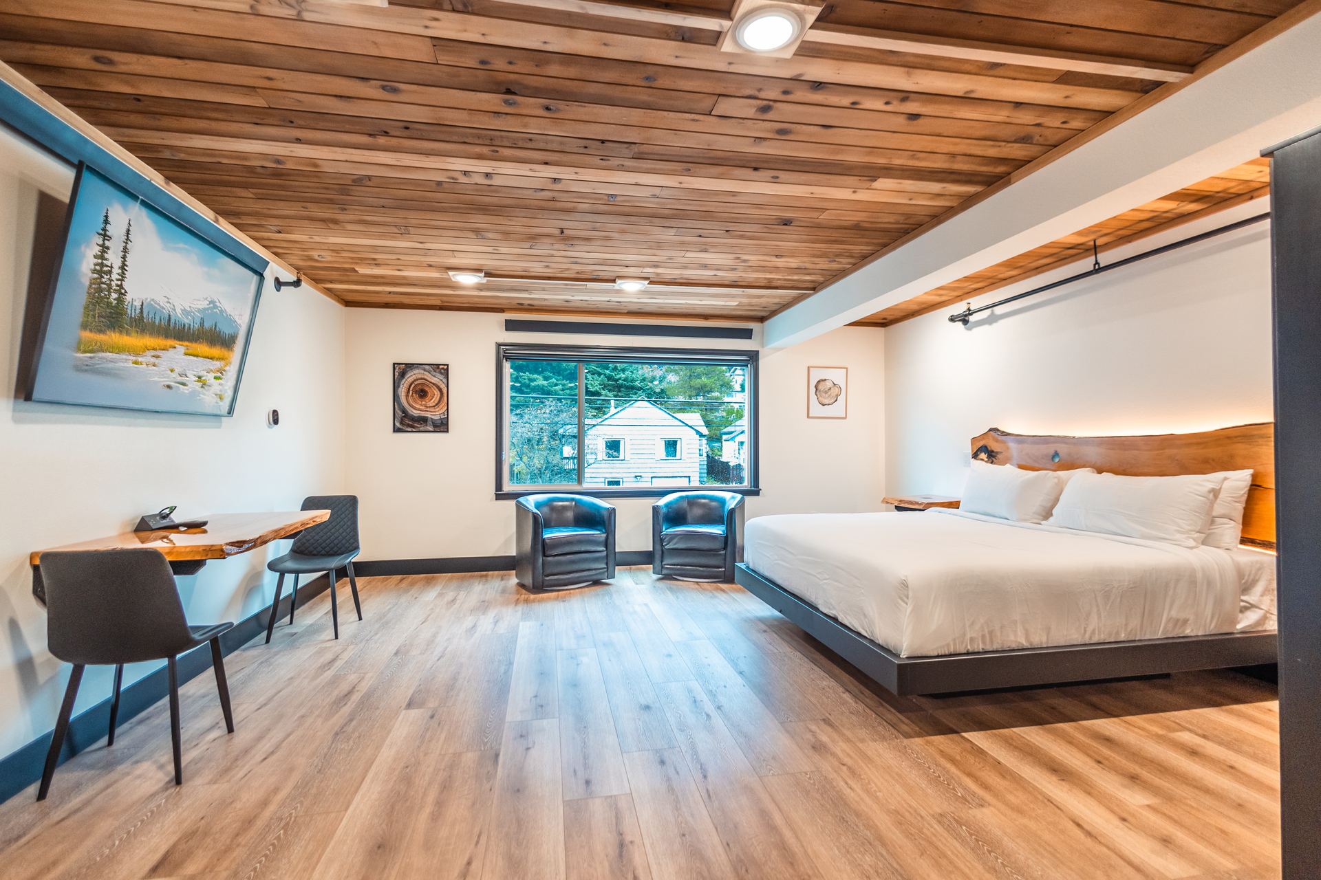 A hotel room with a king size bed , chairs , desk and television.