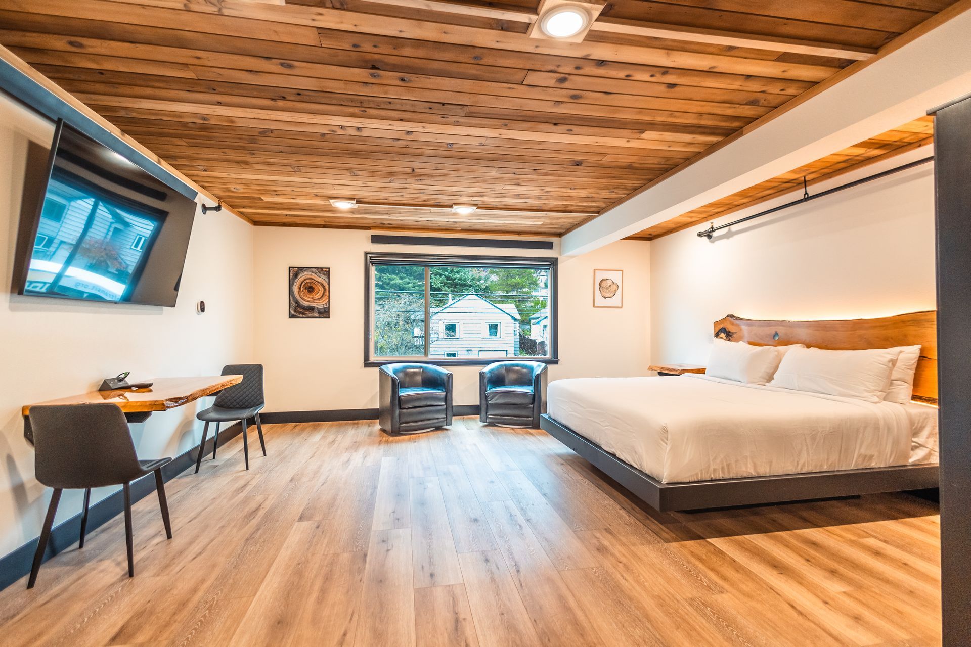 A hotel room with a king size bed , chairs , a desk and a flat screen tv.