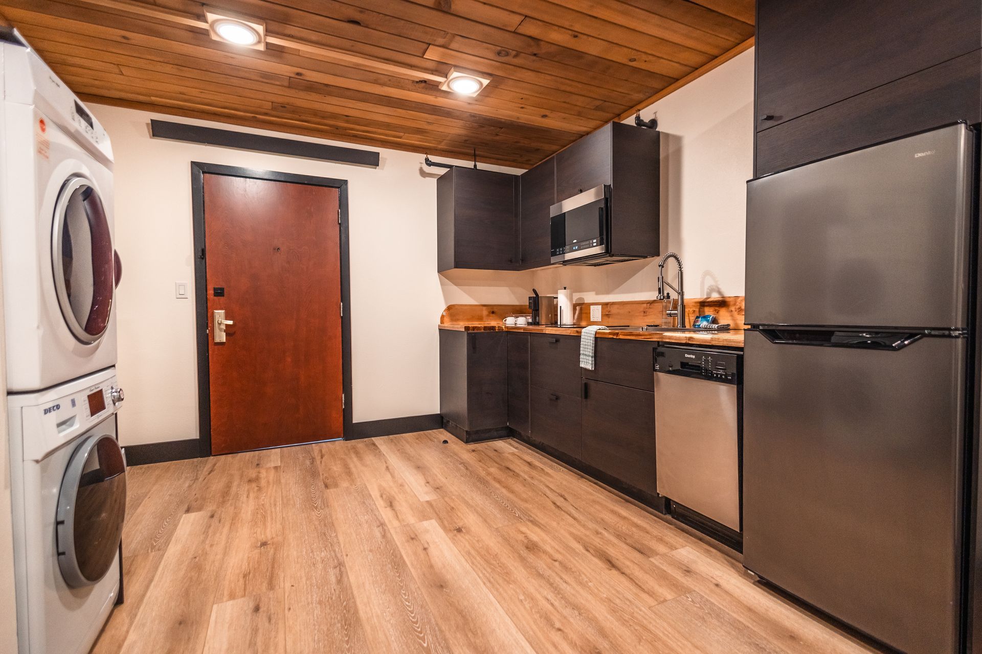 A kitchen with a washer and dryer and a refrigerator.