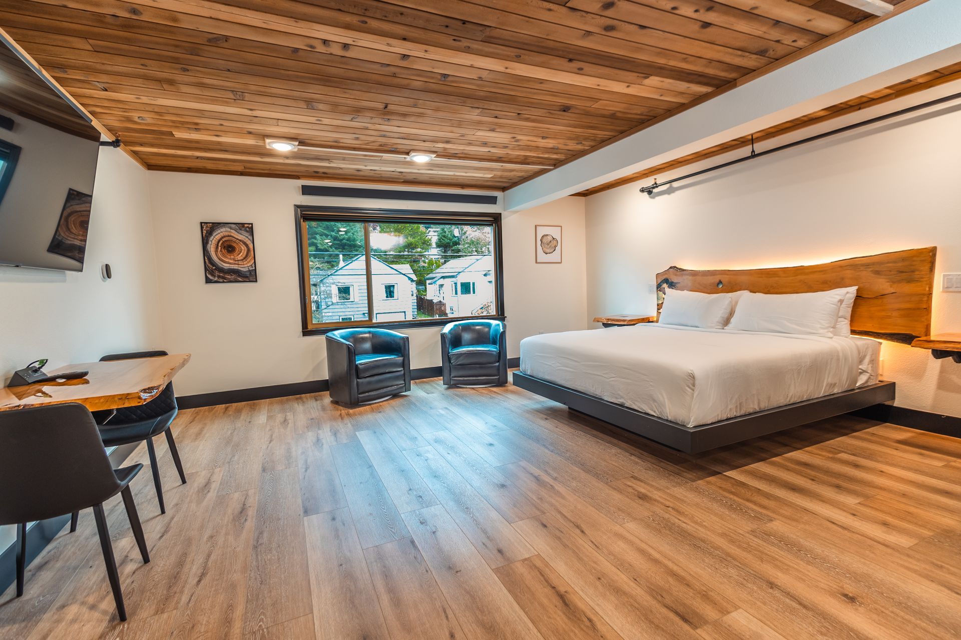 A hotel room with a king size bed , chairs , desk and television.