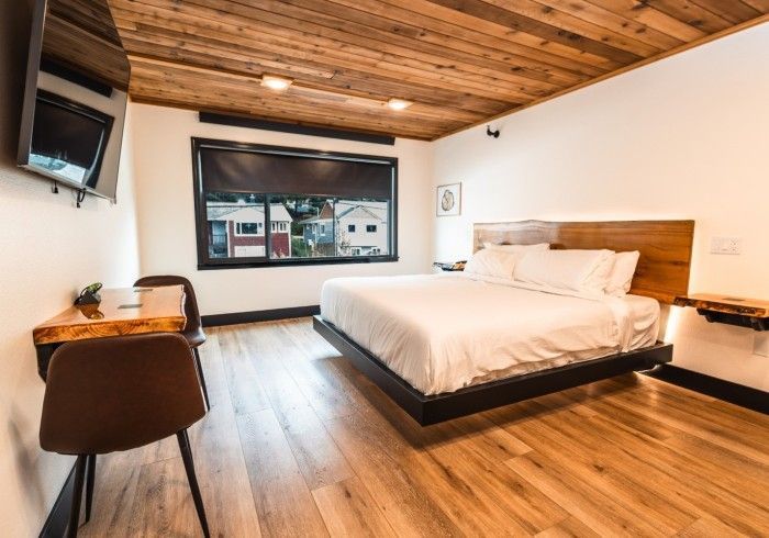 A hotel room with a king size bed , desk , chair and television.