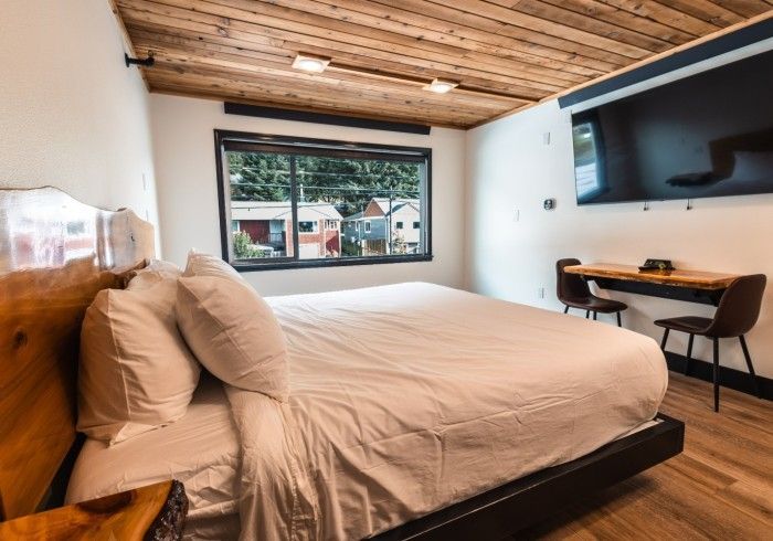 A hotel room with a king size bed , desk and television.