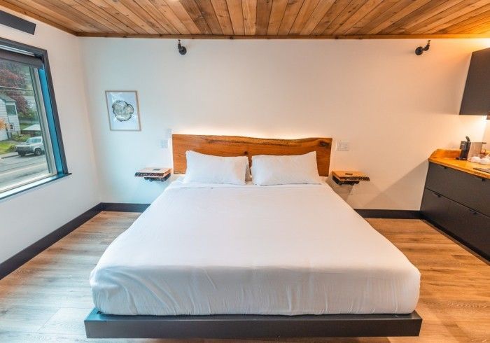 There is a bed in the middle of the room with a wooden headboard.