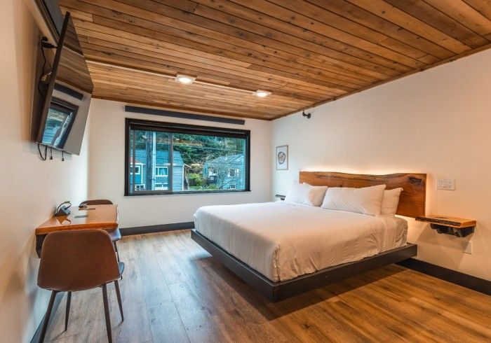 A hotel room with a bed , desk , chair and television.