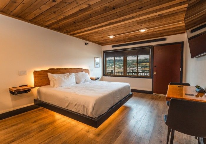 A hotel room with a bed , desk , chair and television.