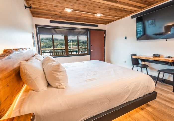 A hotel room with a king size bed , desk and television.