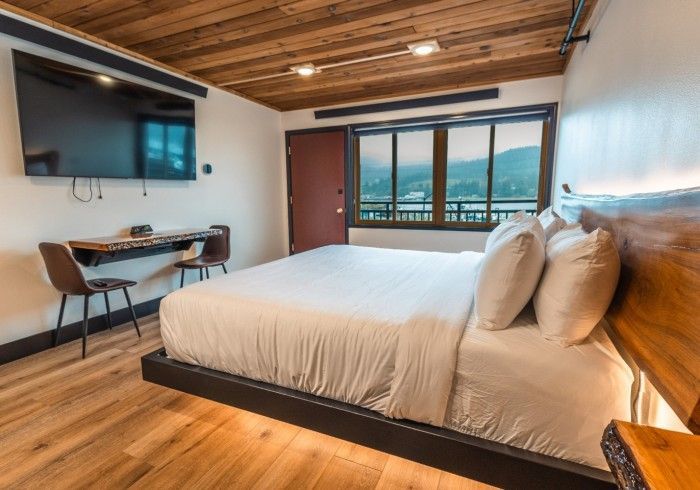 A hotel room with a king size bed , desk and television.