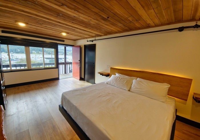 There is a large bed in the middle of the room with a wooden ceiling.