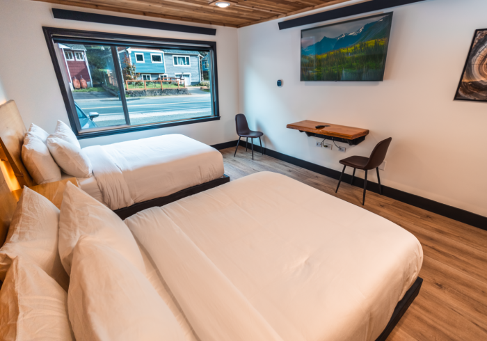 A hotel room with two beds , a desk and a television.