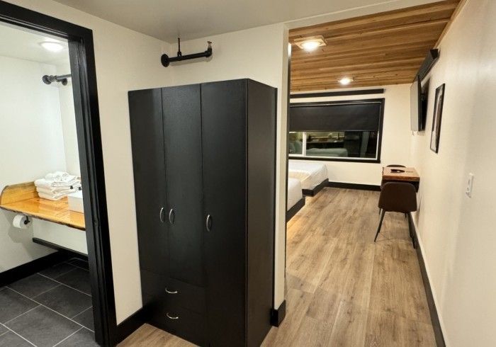 A hotel room with a wardrobe and a desk