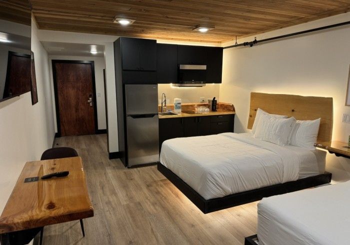 A hotel room with two beds and a kitchen.