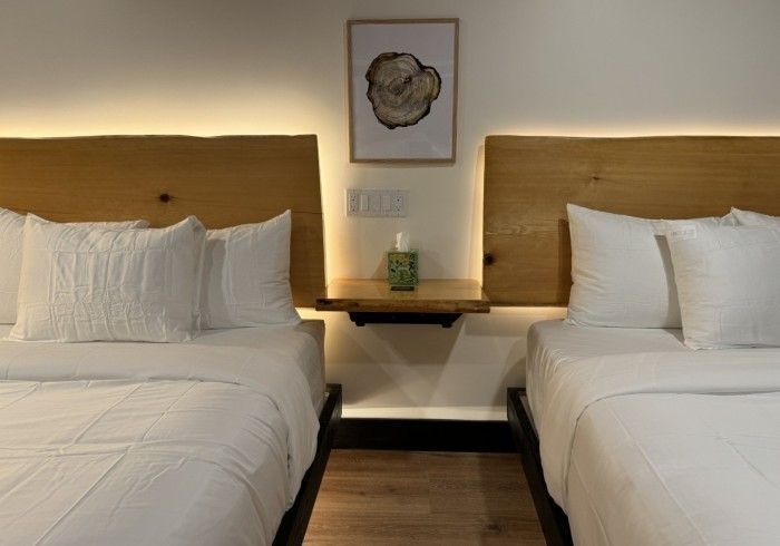 A hotel room with two beds and a wooden headboard.