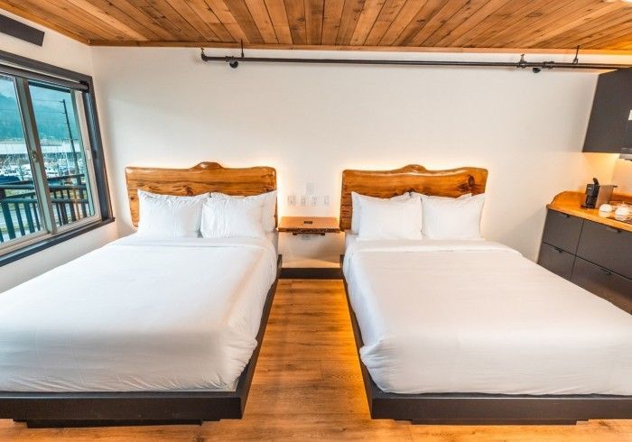 A hotel room with two beds and a wooden ceiling.