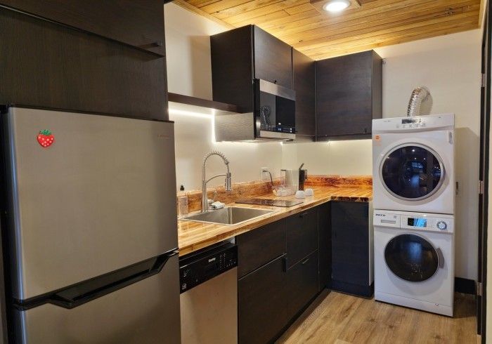 A kitchen with a refrigerator , washer and dryer stacked on top of each other.