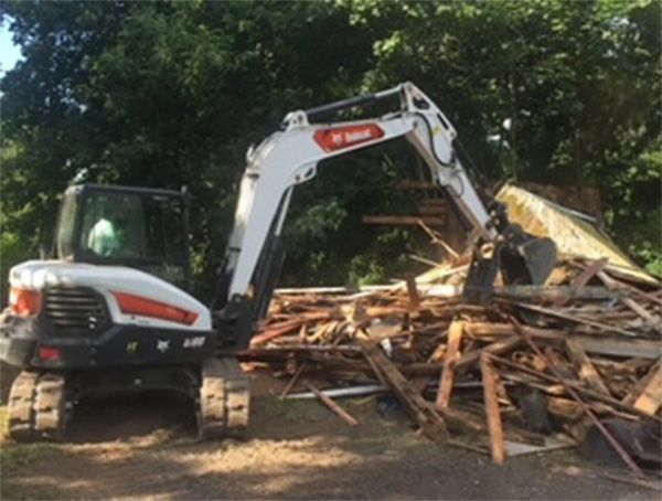 A bobcat excavator is working on a pile of wood