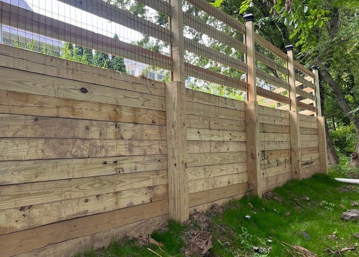 A wooden fence with a wire fence in the backyard.