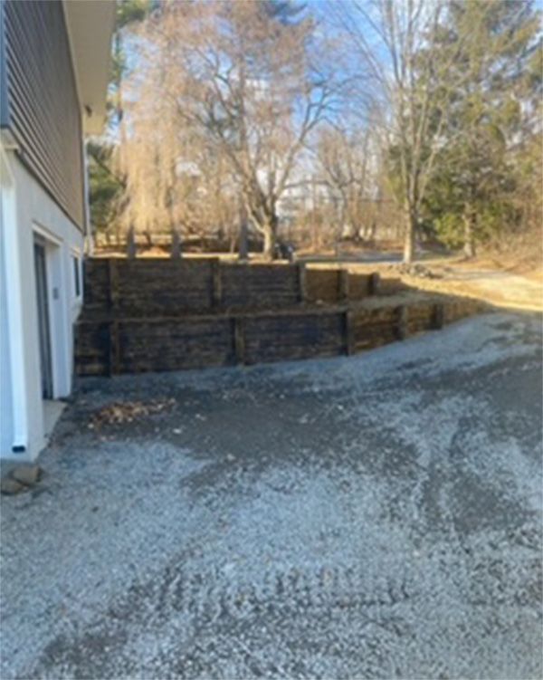 A gravel driveway leading to a house with trees in the background