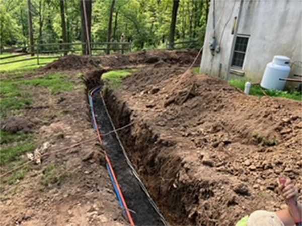 A man is digging a hole in the dirt in front of a house.