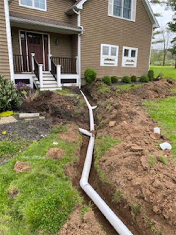 A drain pipe is being installed in front of a house.