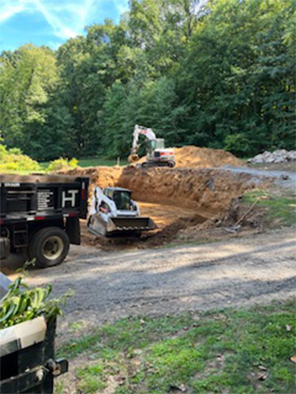 A dump truck is parked next to a bulldozer on a dirt road.