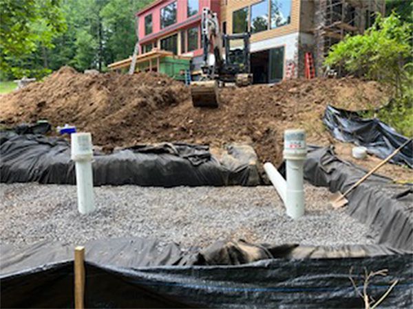 A large pile of dirt is being built in front of a house.