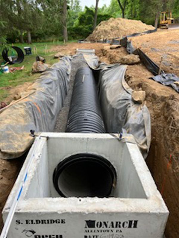 A large black pipe is coming out of a concrete box.