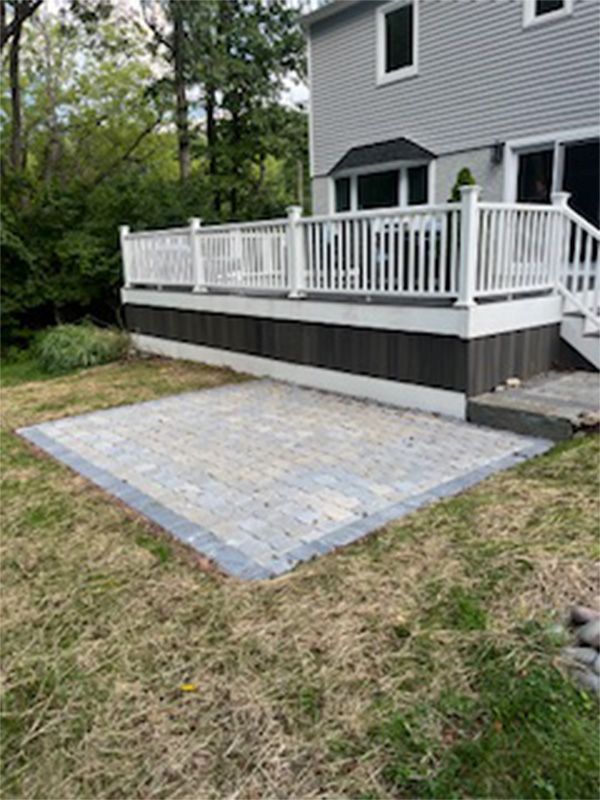 A large deck with a white railing is in the backyard of a house.