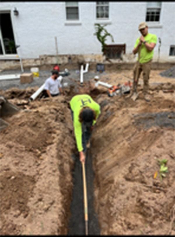 A man in a yellow shirt is digging a hole in the dirt