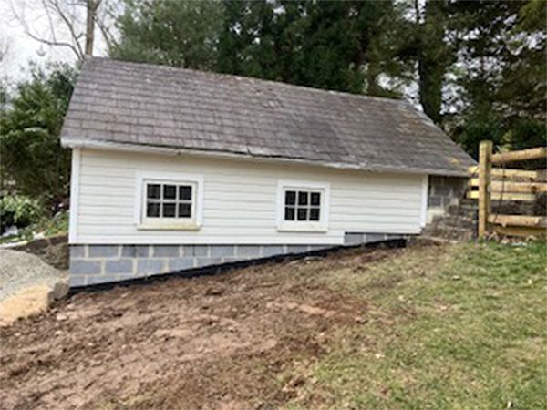 A small white house is sitting on top of a dirt hill.