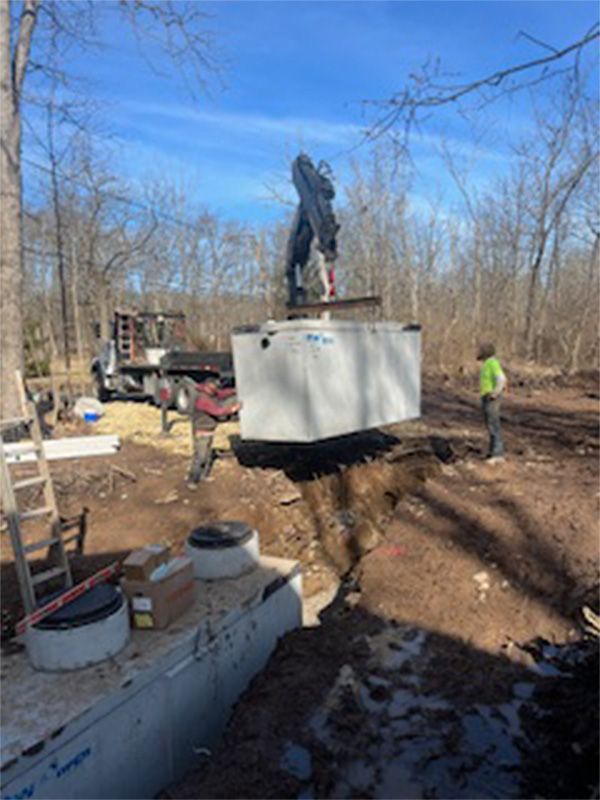 A crane is lifting a large concrete box into the ground.