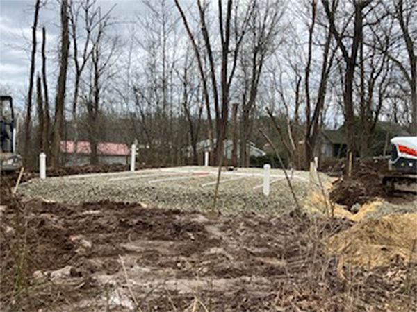A bulldozer is moving dirt in a field with trees in the background.