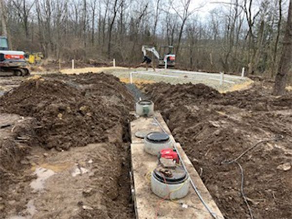 A septic tank is being installed in a dirt field.