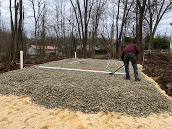 A man is standing on top of a pile of gravel.