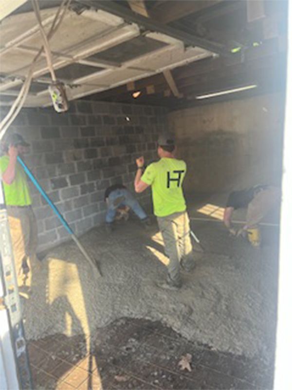 A group of men are working on a concrete floor in a garage.