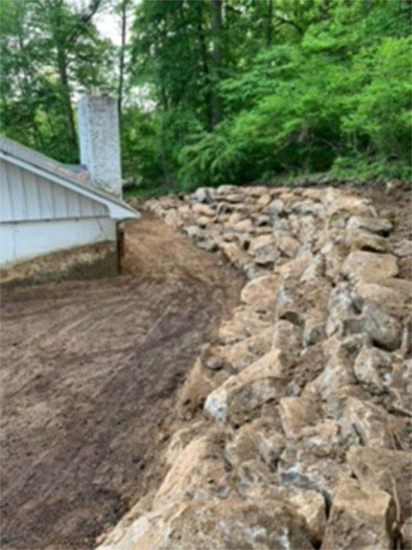 A large pile of rocks is sitting in front of a house.