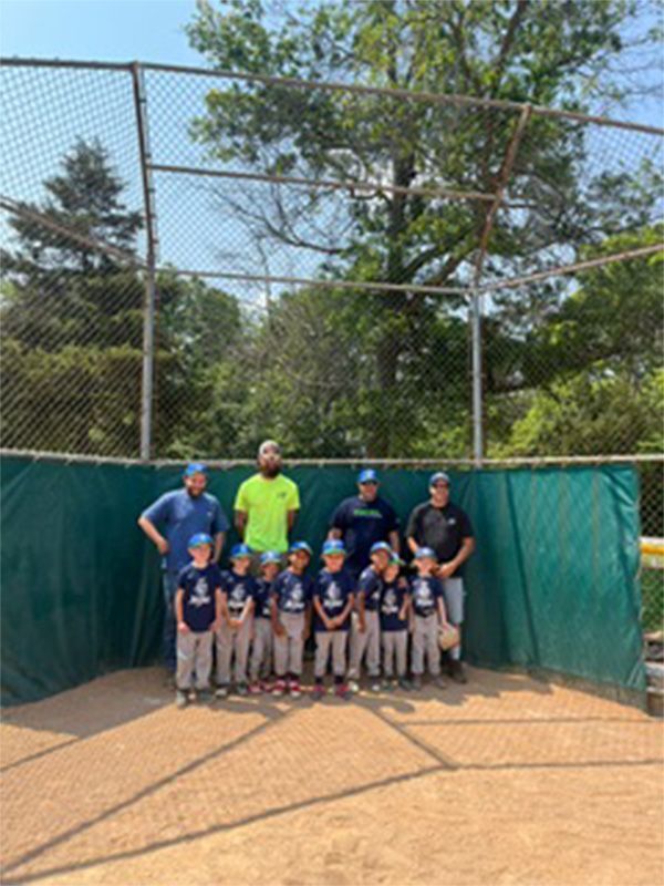 A group of young boys are posing for a picture on a baseball field.