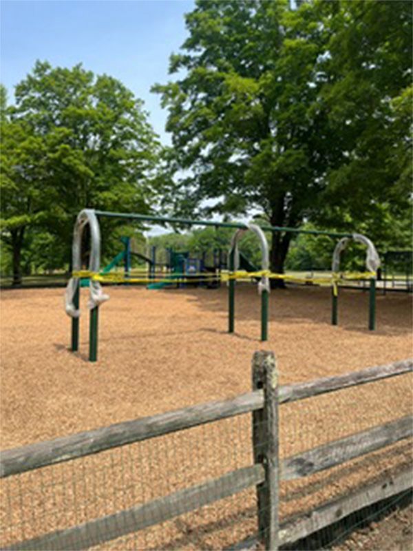 A playground with a wooden fence and yellow tape covering it.