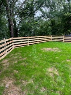 A wooden fence surrounds a lush green yard.