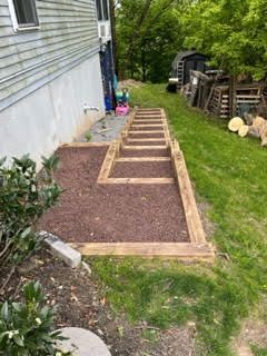 A wooden walkway is being built in the backyard of a house.