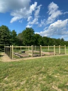 A wooden fence is in the middle of a grassy field.