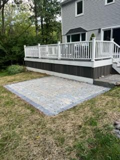 A large deck with a white railing is in the backyard of a house.