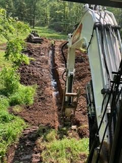 A large excavator is digging a trench in the dirt.