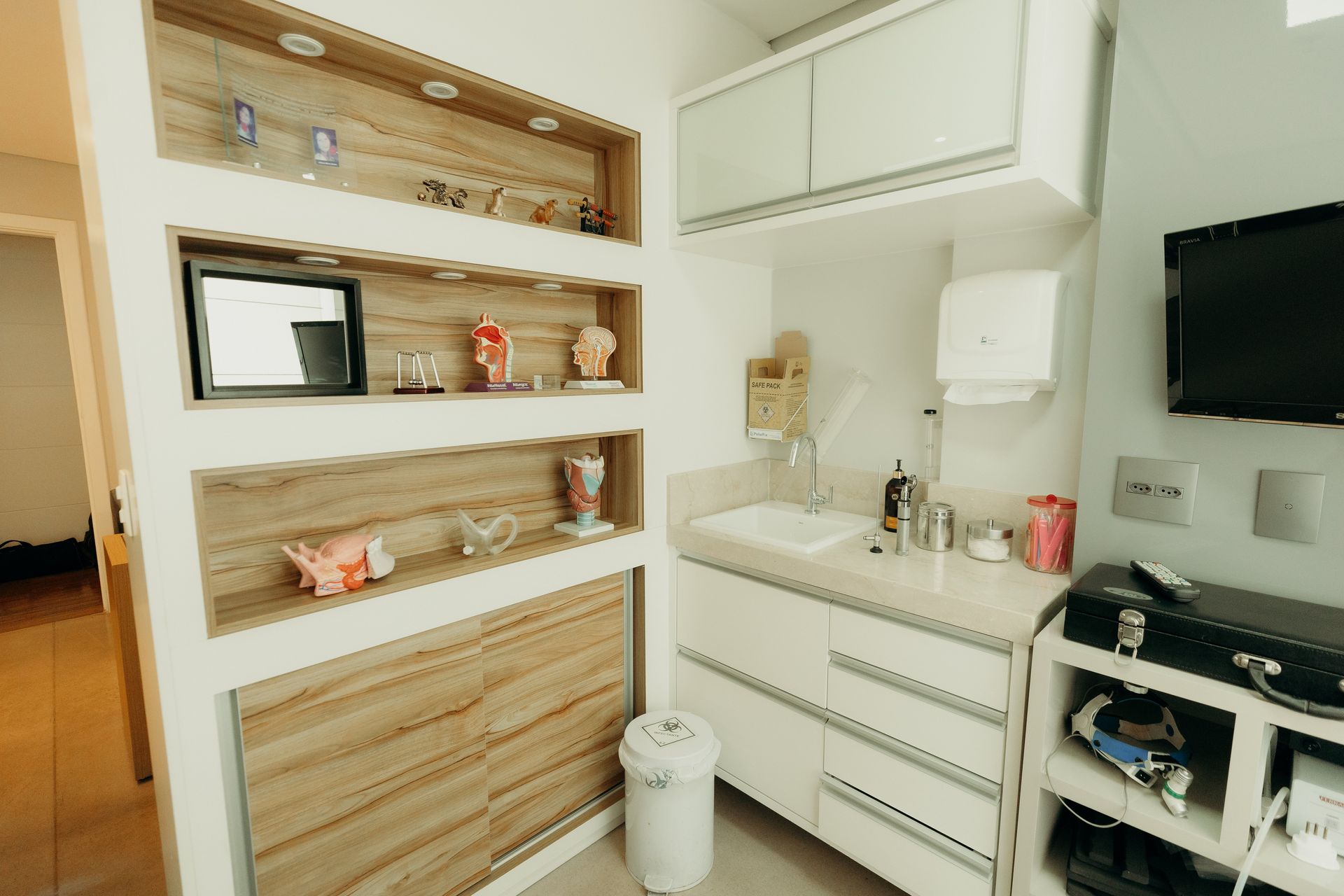 Uma cozinha com armários brancos, uma pia e uma televisão.