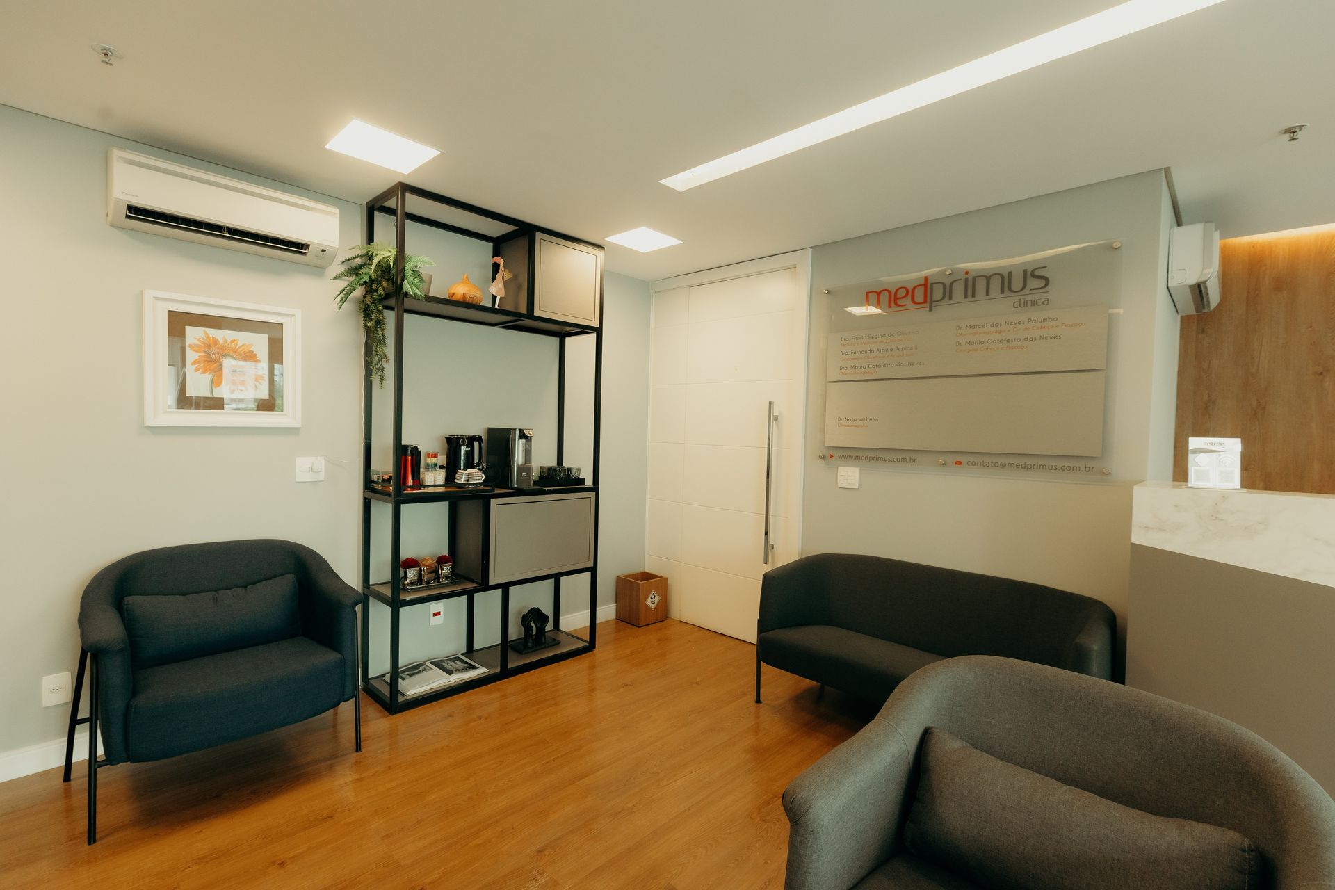 Uma sala de espera com cadeiras, um sofá e uma prateleira.